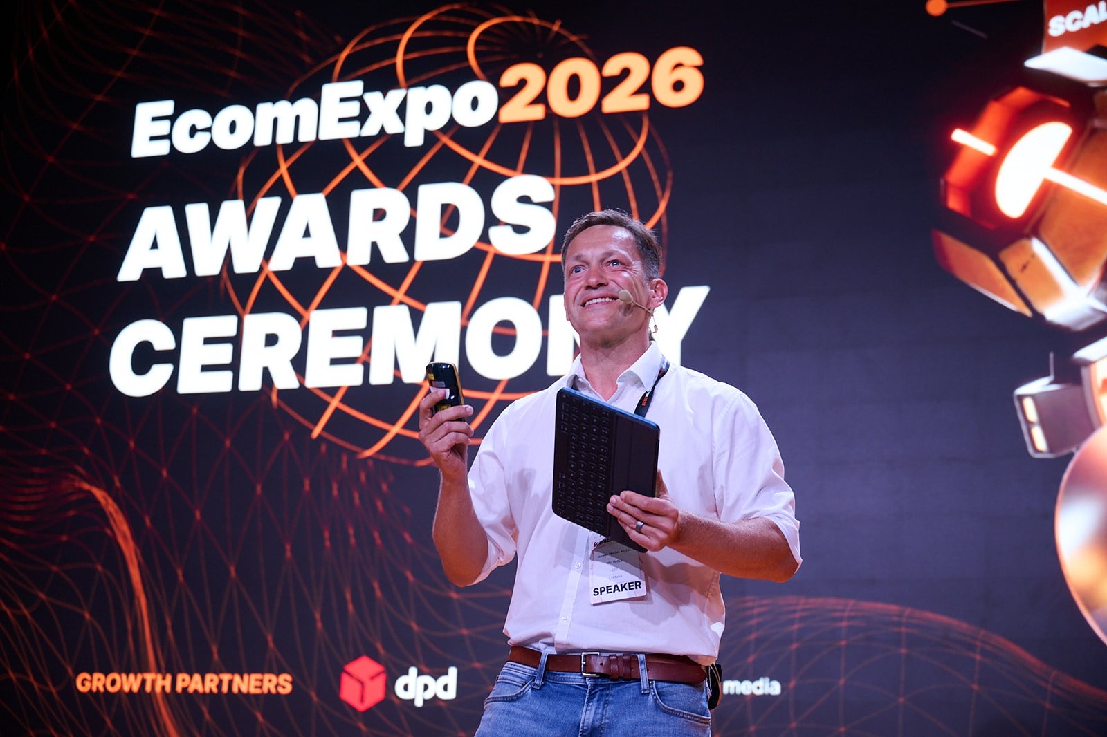The host on stage in front of the EcomExpo 2026 Awards Ceremony screen