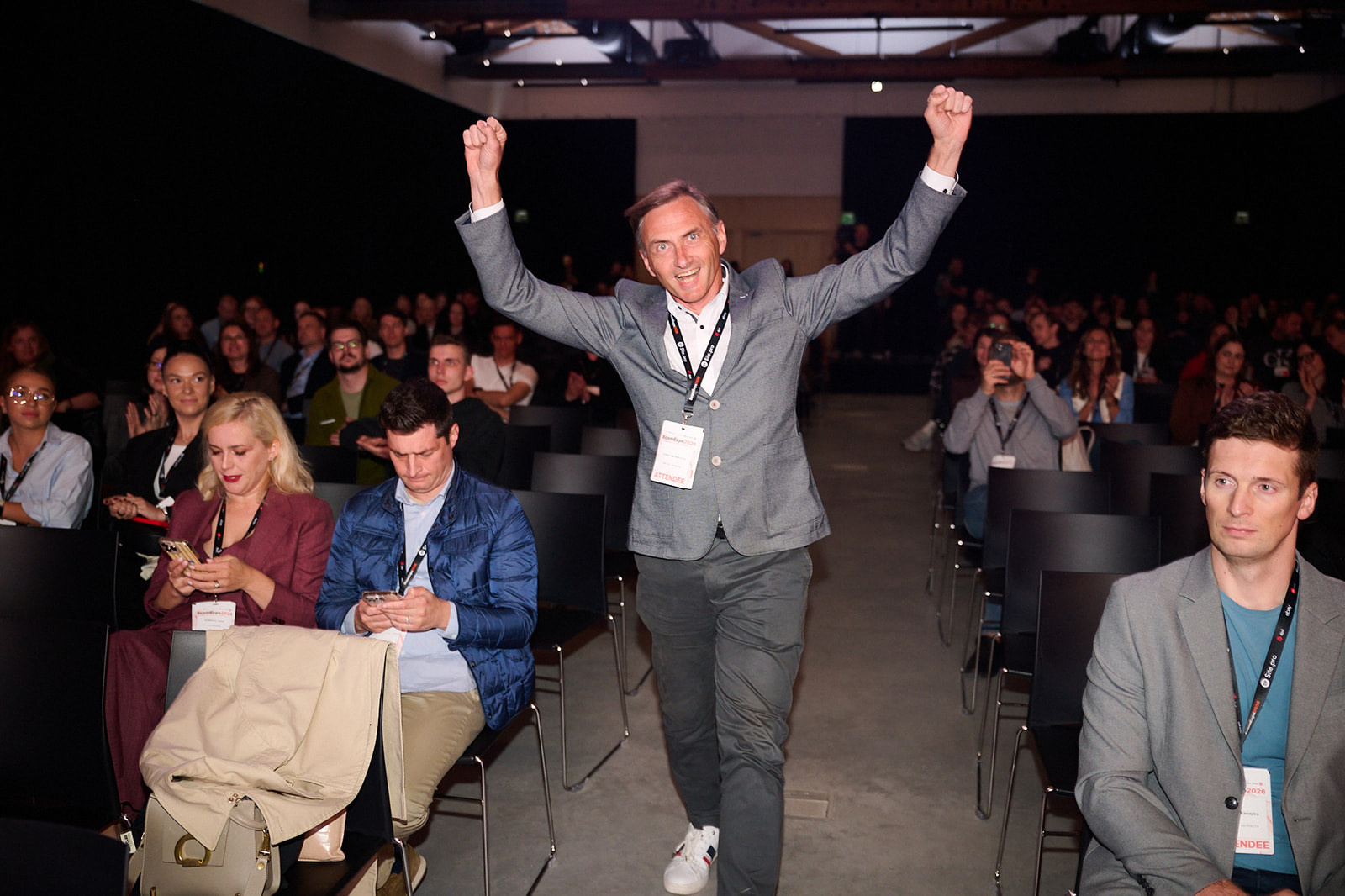 An attendee stands up and cheers in the full main hall at EcomExpo 2026 in Vilnius
